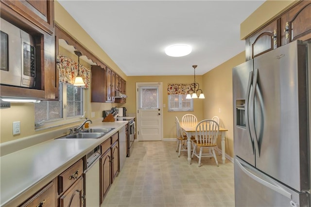 kitchen with pendant lighting, an inviting chandelier, stainless steel appliances, and sink