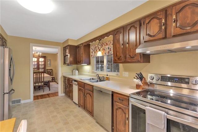 kitchen featuring appliances with stainless steel finishes, an inviting chandelier, a healthy amount of sunlight, and sink