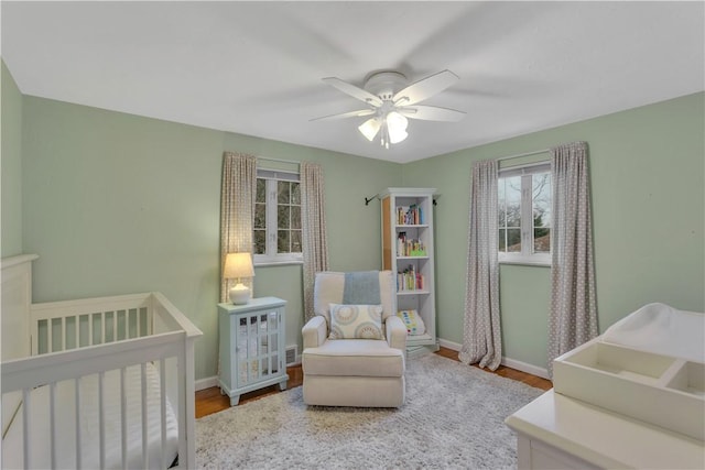 bedroom featuring ceiling fan, wood-type flooring, and a crib