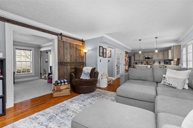 living room featuring a barn door, hardwood / wood-style flooring, and ornamental molding