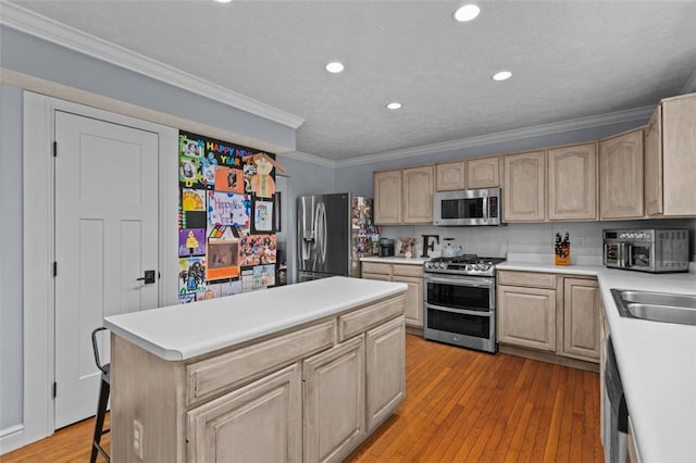 kitchen featuring light brown cabinets, stainless steel appliances, a breakfast bar area, and light hardwood / wood-style flooring