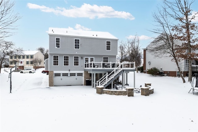 snow covered back of property with a wooden deck and a garage