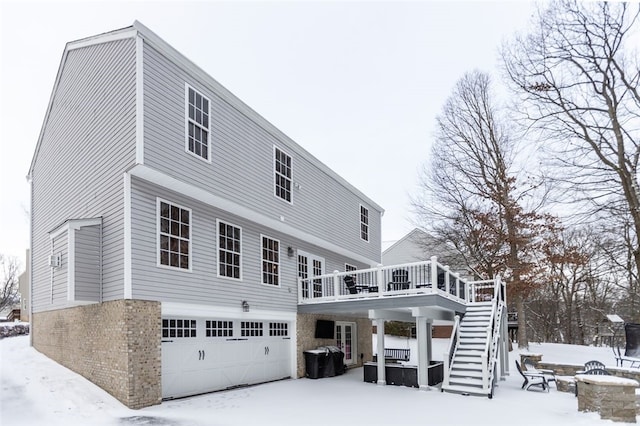 snow covered house featuring a wooden deck, a fire pit, and a garage