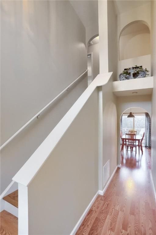 hallway with hardwood / wood-style floors and a high ceiling