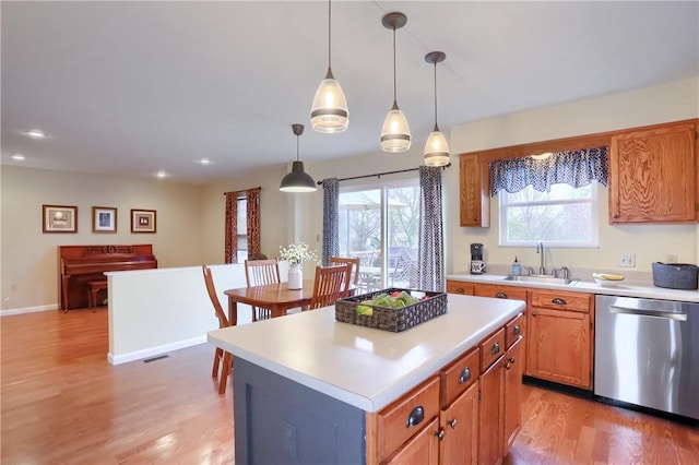 kitchen with stainless steel dishwasher, sink, light hardwood / wood-style flooring, a kitchen island, and hanging light fixtures