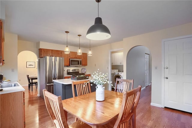 dining area featuring independent washer and dryer, dark hardwood / wood-style floors, and sink