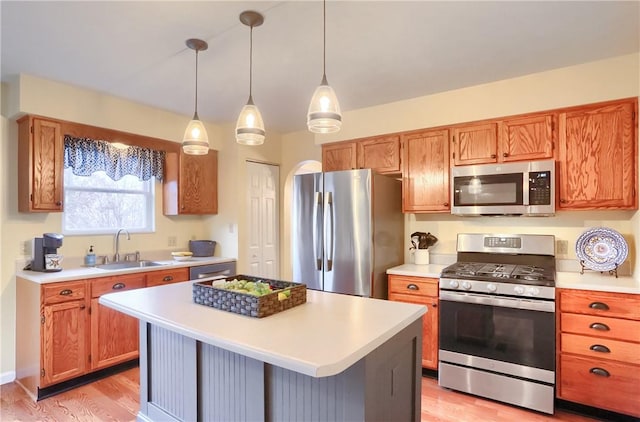 kitchen with a kitchen bar, stainless steel appliances, sink, a kitchen island, and hanging light fixtures