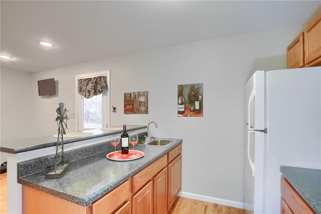 kitchen featuring kitchen peninsula, white refrigerator, light hardwood / wood-style floors, and sink