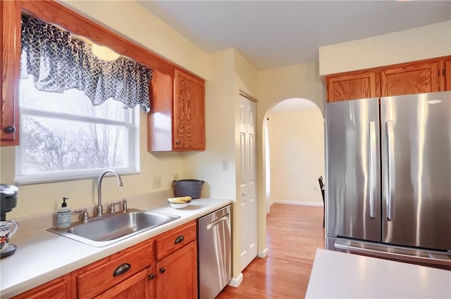 kitchen with appliances with stainless steel finishes, light hardwood / wood-style flooring, and sink