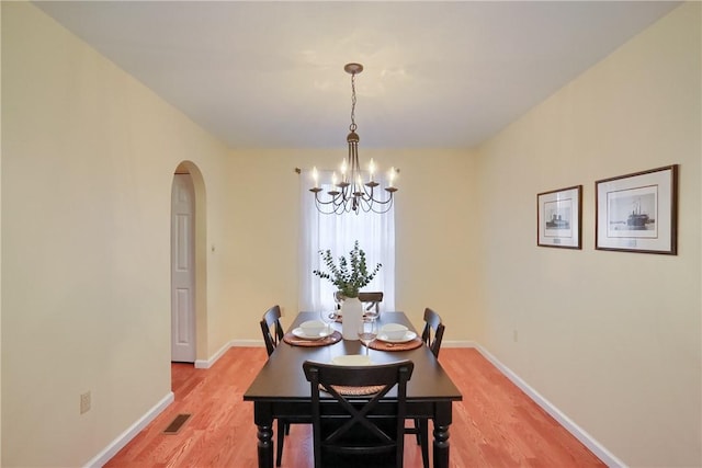 dining space with light hardwood / wood-style floors and an inviting chandelier