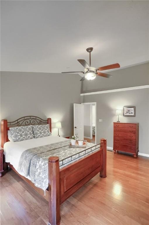 bedroom with ceiling fan, vaulted ceiling, and light hardwood / wood-style flooring