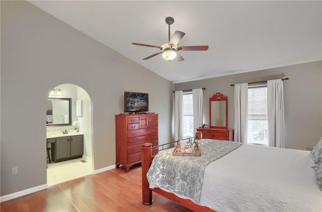 bedroom with lofted ceiling, ensuite bathroom, sink, ceiling fan, and wood-type flooring