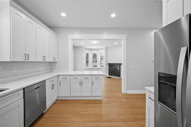 kitchen featuring kitchen peninsula, white cabinets, stainless steel appliances, and light hardwood / wood-style floors