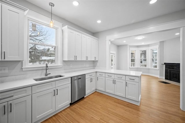 kitchen with stainless steel dishwasher, sink, pendant lighting, light hardwood / wood-style flooring, and white cabinetry