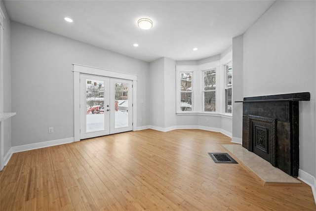 unfurnished living room featuring french doors and light wood-type flooring