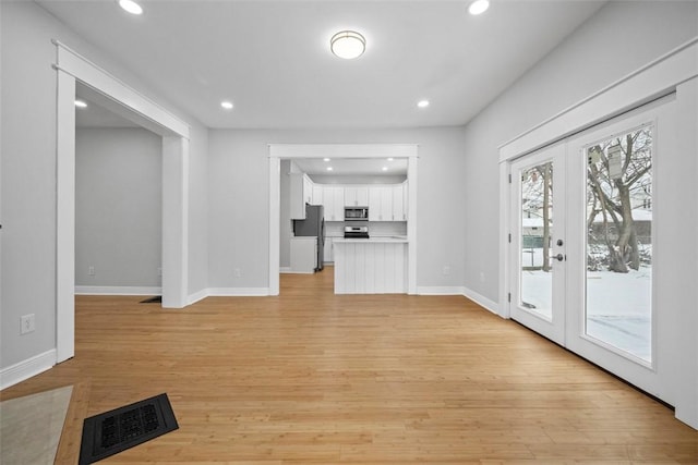 unfurnished living room featuring french doors and light hardwood / wood-style floors