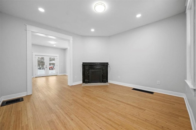 unfurnished living room with light hardwood / wood-style flooring and french doors