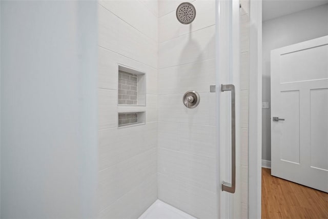 bathroom featuring hardwood / wood-style flooring and a tile shower