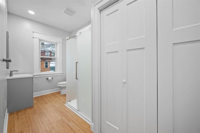 bathroom featuring hardwood / wood-style flooring, vanity, an enclosed shower, and toilet