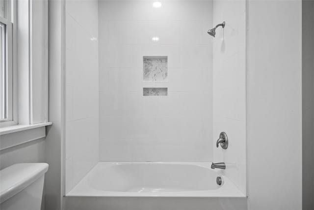 bathroom with tiled shower / bath combo and toilet