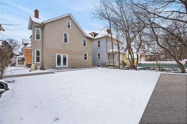 snow covered back of property featuring french doors