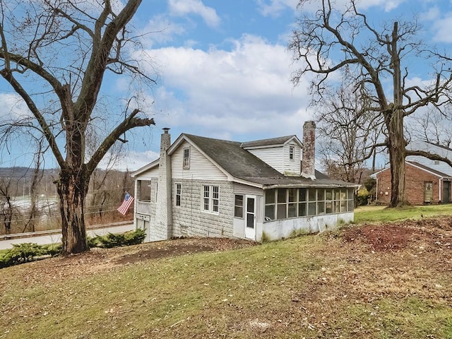 rear view of property featuring a yard and a sunroom