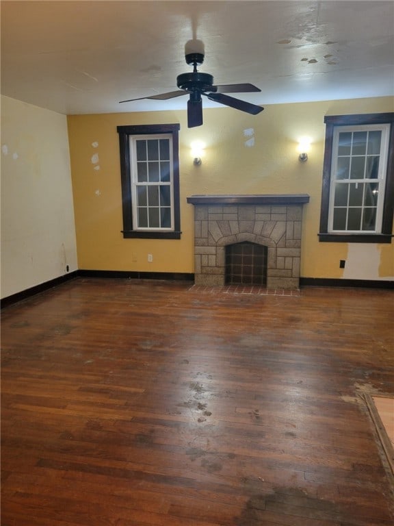 unfurnished living room featuring a fireplace, ceiling fan, and dark wood-type flooring