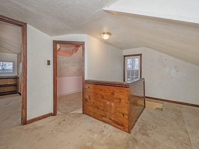 additional living space featuring a textured ceiling and vaulted ceiling