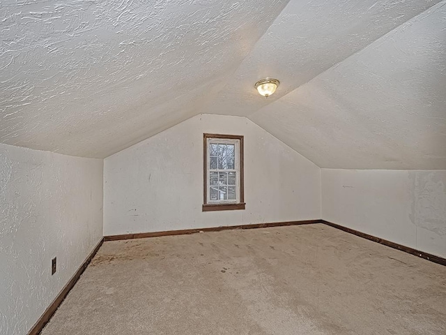 additional living space featuring lofted ceiling, carpet, and a textured ceiling