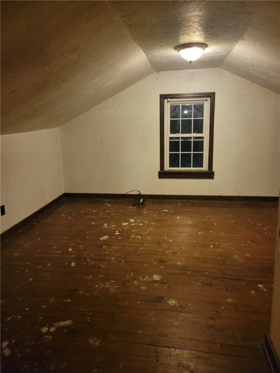 additional living space featuring lofted ceiling, dark hardwood / wood-style flooring, and a textured ceiling