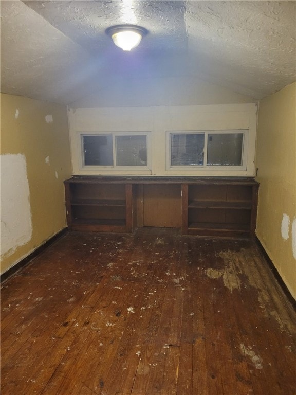 miscellaneous room with vaulted ceiling, dark hardwood / wood-style flooring, and a textured ceiling