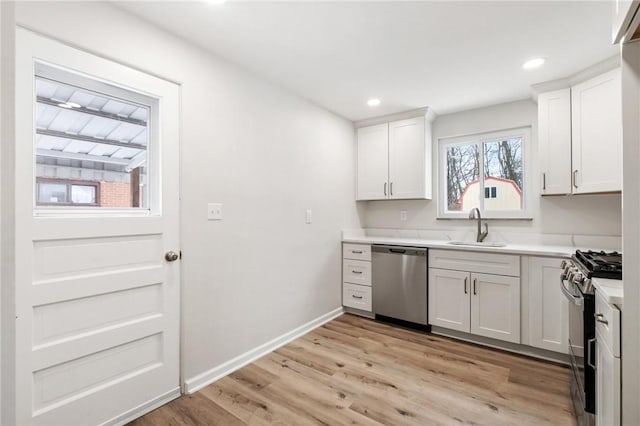 kitchen with white cabinetry, sink, light hardwood / wood-style flooring, and appliances with stainless steel finishes