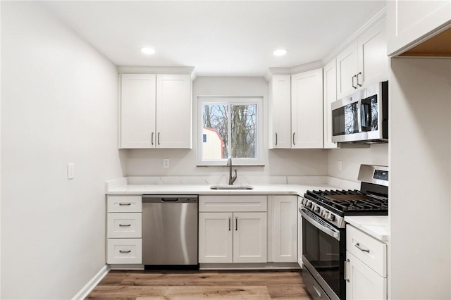 kitchen featuring white cabinets, light wood-type flooring, stainless steel appliances, and sink