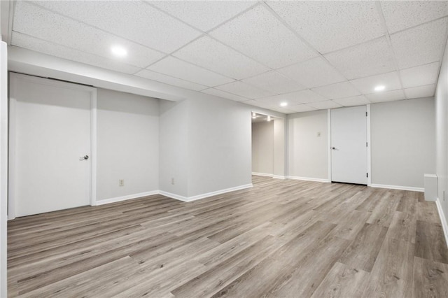 basement with light hardwood / wood-style flooring and a drop ceiling