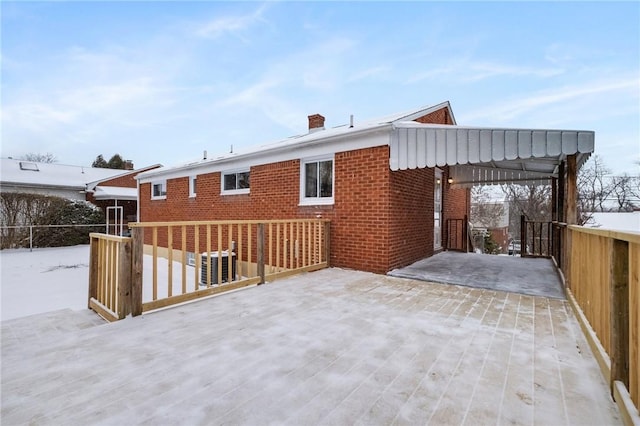 snow covered rear of property featuring central AC