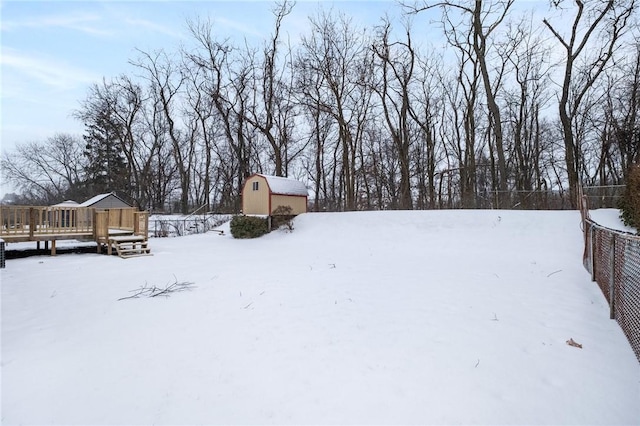 yard covered in snow featuring an outdoor structure and a wooden deck