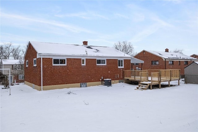 snow covered rear of property with central AC unit and a wooden deck