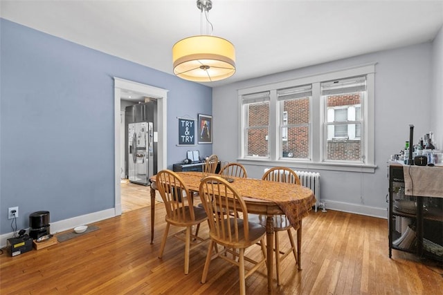 dining area with radiator heating unit and light wood-type flooring