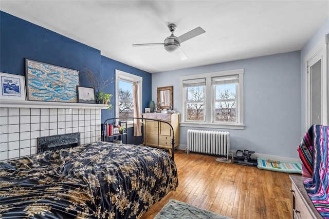 bedroom with hardwood / wood-style flooring, ceiling fan, and radiator heating unit