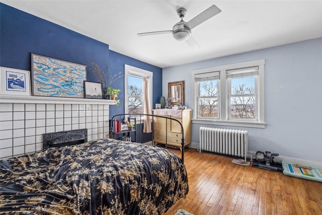 bedroom featuring radiator, ceiling fan, hardwood / wood-style floors, and multiple windows