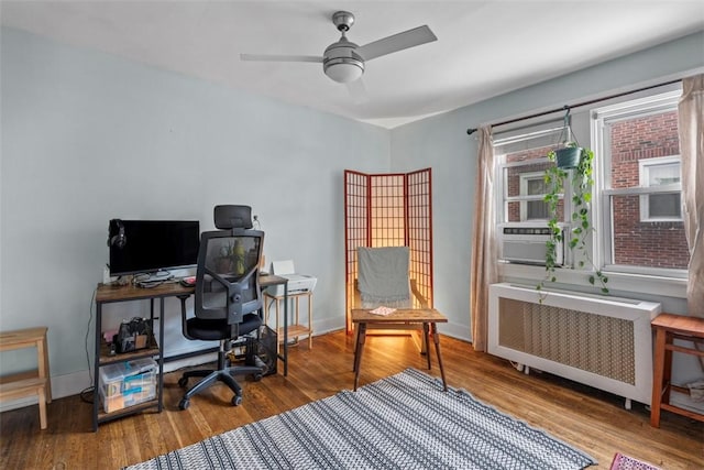 home office featuring hardwood / wood-style floors, ceiling fan, cooling unit, and radiator heating unit