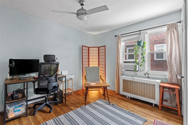 office space featuring hardwood / wood-style flooring, ceiling fan, cooling unit, and radiator