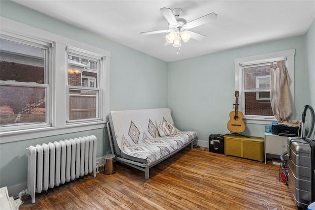 living area featuring wood-type flooring, radiator, and ceiling fan