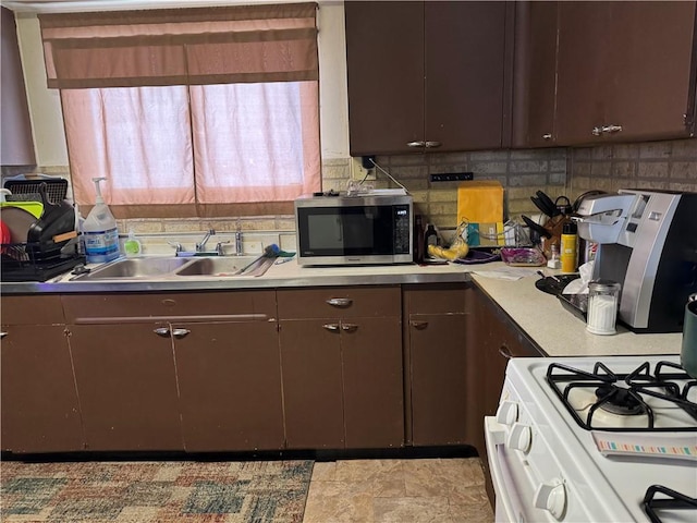 kitchen with tasteful backsplash, white gas range, sink, and dark brown cabinets