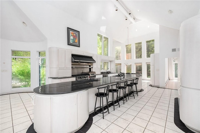 kitchen with white cabinetry, high vaulted ceiling, light tile patterned floors, and ventilation hood