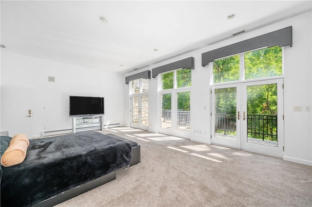 carpeted bedroom with a baseboard heating unit, access to exterior, a towering ceiling, and french doors