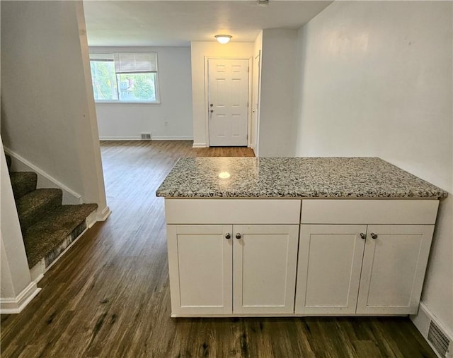 kitchen with white cabinets, light stone countertops, and dark wood-type flooring