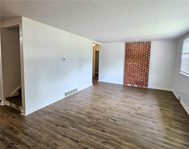 empty room featuring dark hardwood / wood-style flooring and a brick fireplace