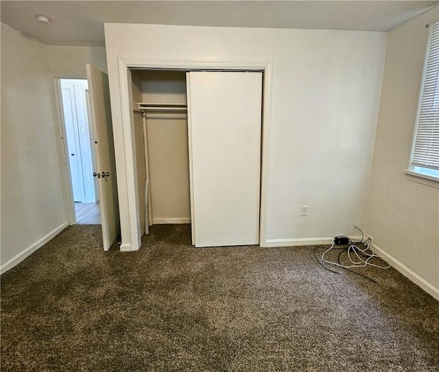 unfurnished bedroom with dark carpet and a closet