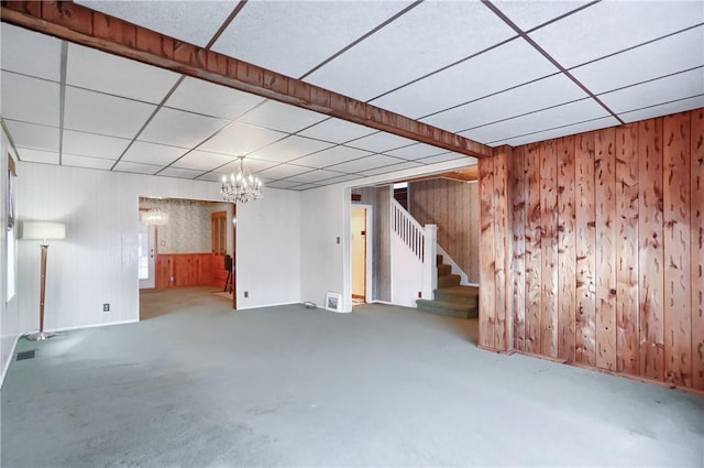 basement with an inviting chandelier, a paneled ceiling, carpet flooring, and wood walls